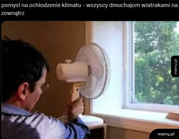 Mężczyzna trzyma wentylator skierowany na otwarte okno.