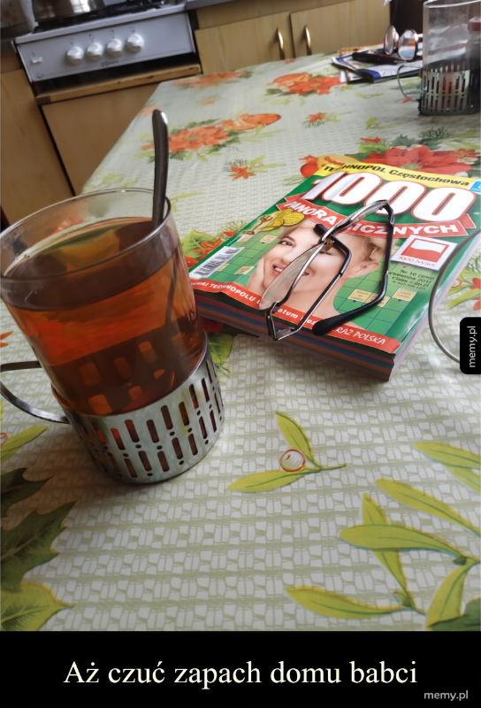 Szklanka herbaty na stole z gazetą i okularami.