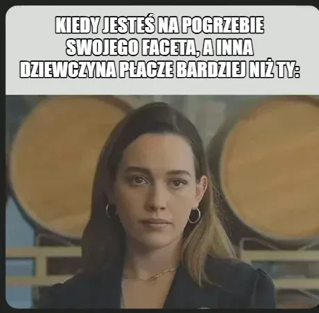 Kobieta z poważnym wyrazem twarzy w tle z beczkami.