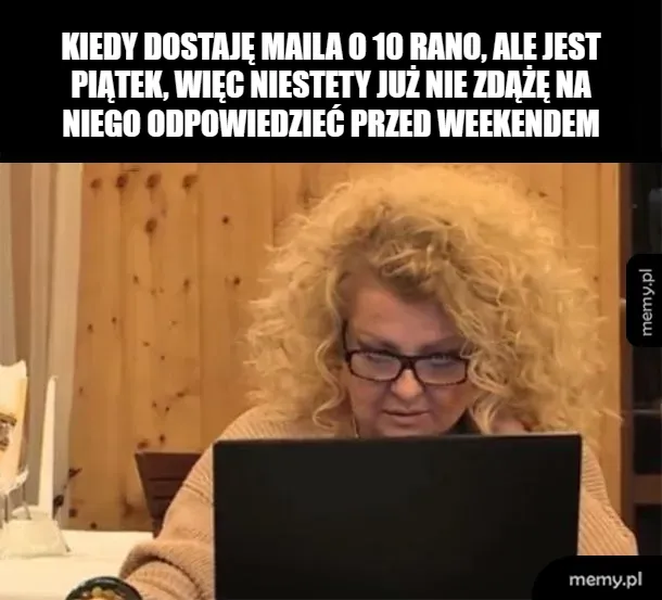 Osoba z kręconymi włosami siedzi przy biurku, patrząc na laptopa.