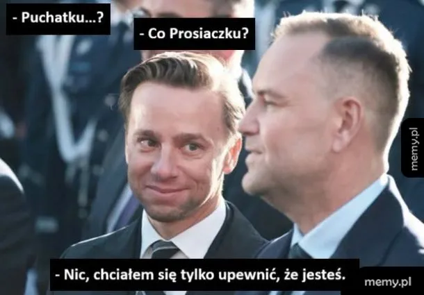 Dwóch mężczyzn w garniturach rozmawia, jeden z nich uśmiecha się.