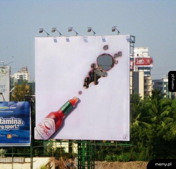Billboard reklamujący ostry sos z wypaloną dziurą w kształcie wystrzału.
