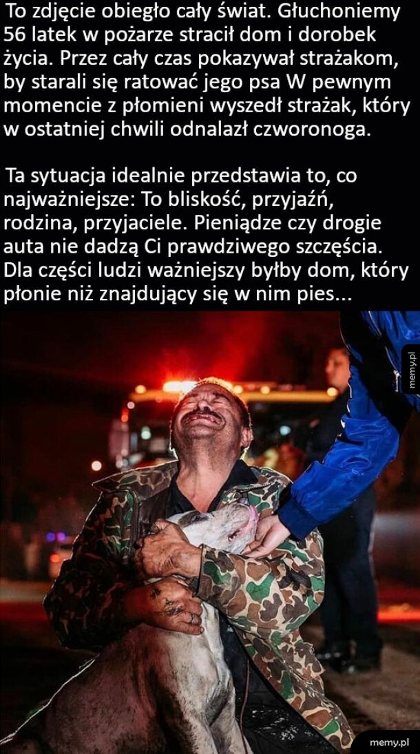 Płaczący mężczyzna przytula uratowanego z pożaru psa.