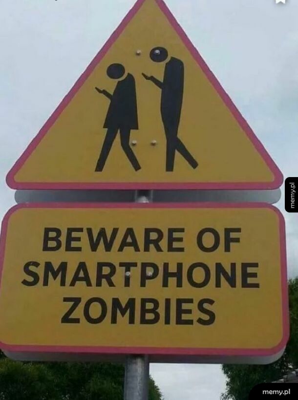 Znak drogowy ostrzegający przed pieszymi wpatrzonymi w smartfony z napisem BEWARE OF SMARTPHONE ZOMBIES