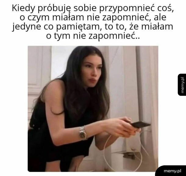 Kobieta z ciemnymi włosami wpatrzona w punkt, trzymająca w ręku pilot lub telefon.