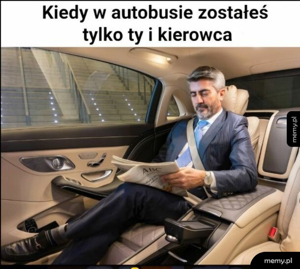 Elegancki mężczyzna w garniturze siedzi w luksusowym samochodzie i czyta gazetę.