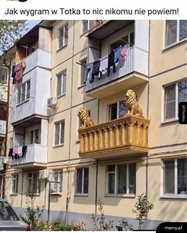 Balkon z pałacowymi kolumnami i lwami na zwykłym bloku z wielkiej płyty.