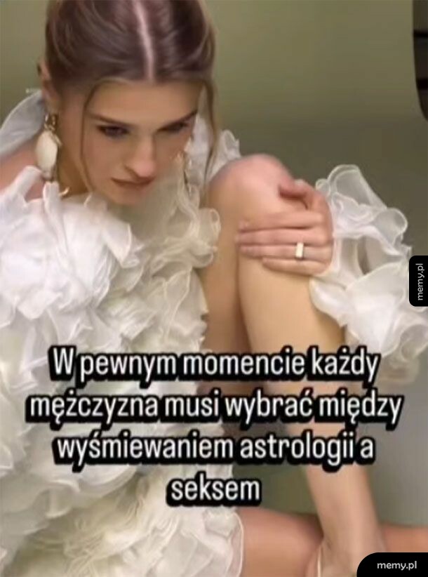 Kobieta w białej, ozdobnej sukni siedzi skulona zamyślona.