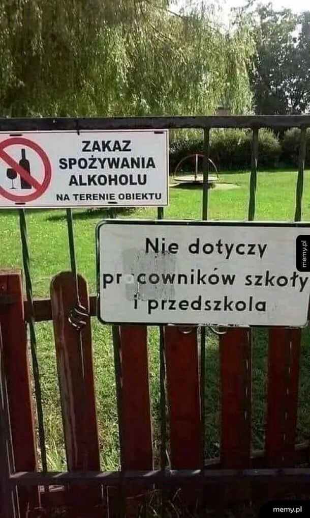 Tablice informacyjne z zakazem spożywania alkoholu na ogrodzeniu placu zabaw.