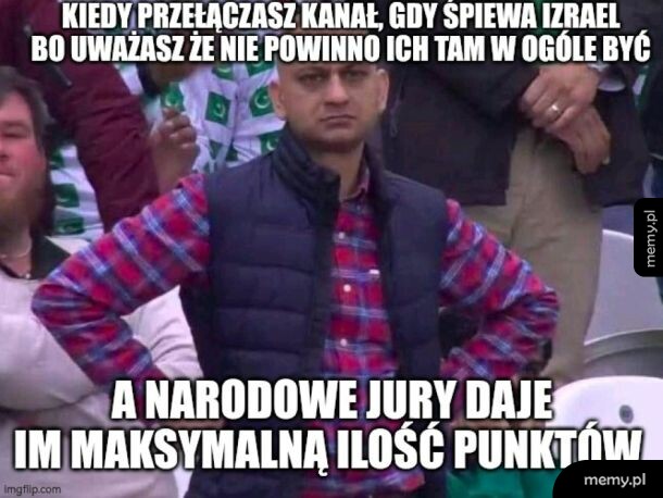Mężczyzna z rękami na biodrach patrzy z poirytowaniem podczas oglądania telewizji.